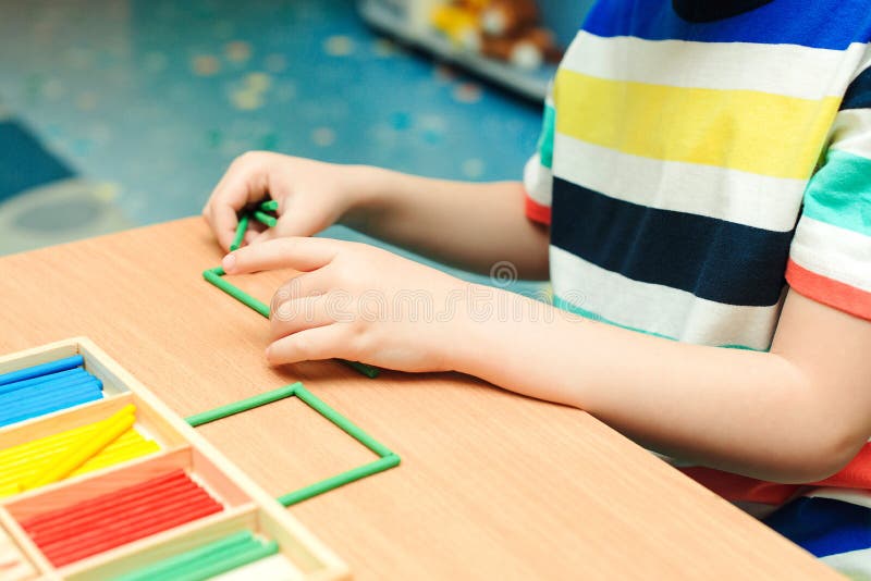 Child makes geometric forms from colorful sticks. Preschool education and development. Primary class of school. Kid at math class royalty free stock images Child makes geometric forms from colorful sticks. Preschool education and development. Primary class of school. Kid at math class royalty free stock images