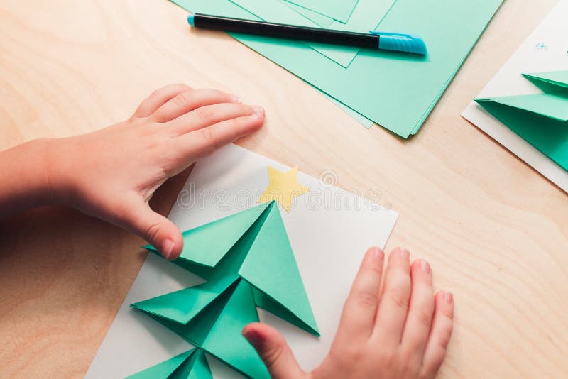 Child making Christmas card from paper. Step 6