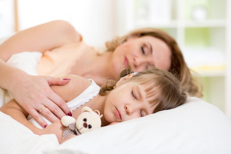 Child with mother preparing for napping on bed