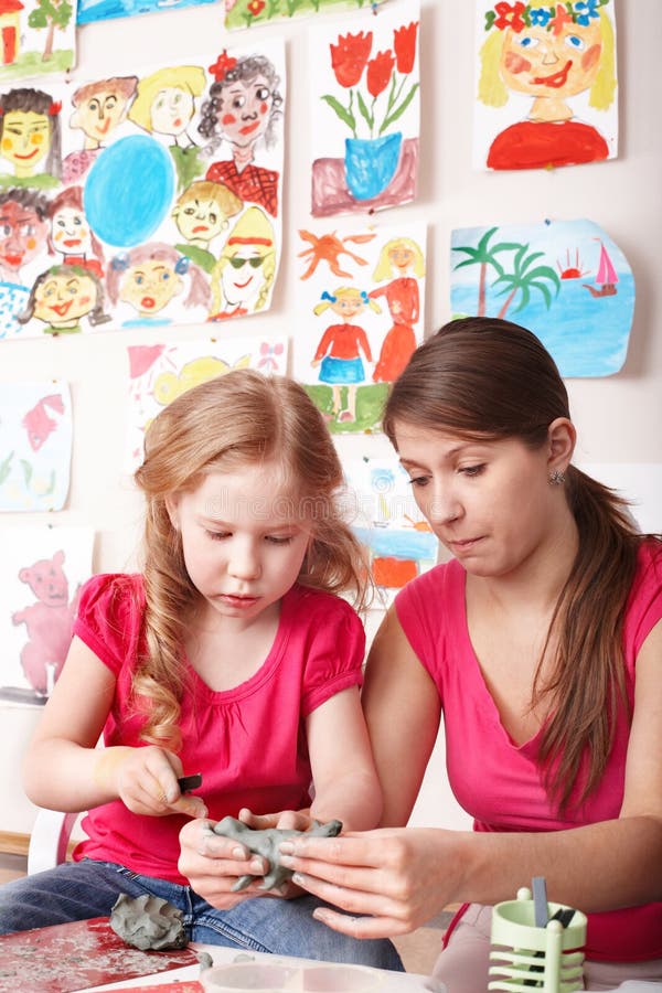 Child mould from clay with teacher.