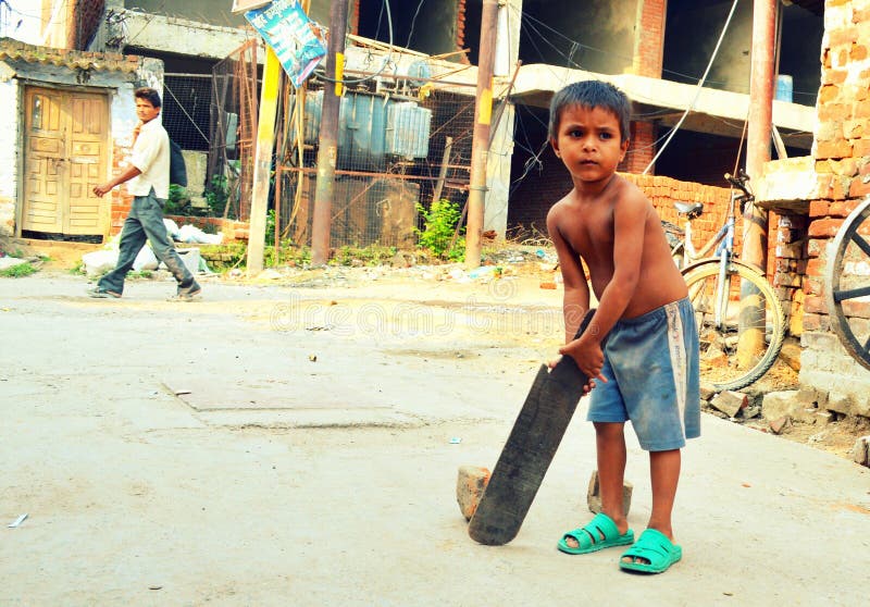 Child obsession for cricket in India. A poor child batting in streets of Lucknow city in India. Cricket is the most favorite game amongst children in India stock photography Child obsession for cricket in India. A poor child batting in streets of Lucknow city in India. Cricket is the most favorite game amongst children in India stock photography