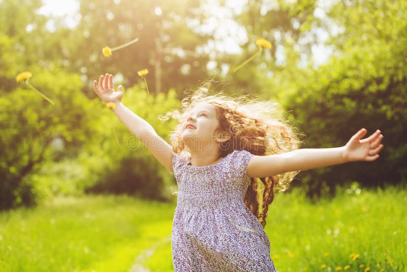 Child outstretched arms enjoying flying yellow dandelion