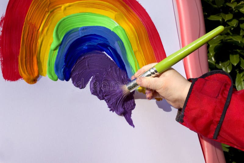 Child painting rainbow on easel in garden