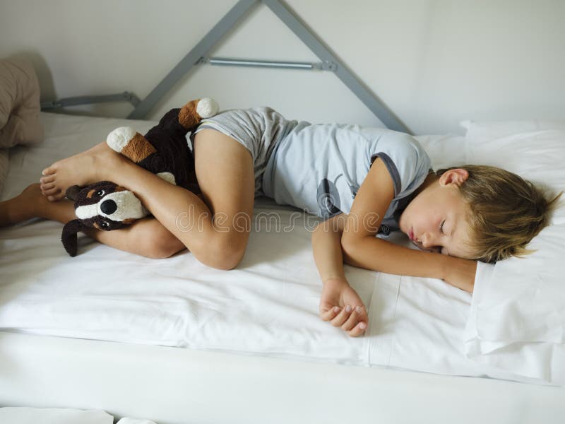 Child in Pajamas Sleeping in His Bed without Blankets Stock Photo