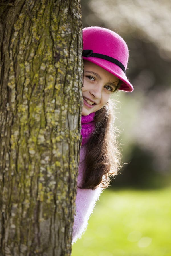 Beautiful child peeking behind a tree