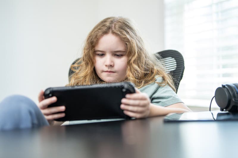 Child play game. Kid gaming online game. Boy gamer using a game console. Kid play with a game gadget at home. stock photo