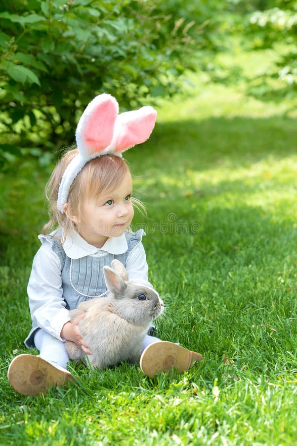 Children play with real rabbit. Laughing child at Easter egg hunt with pet bunny