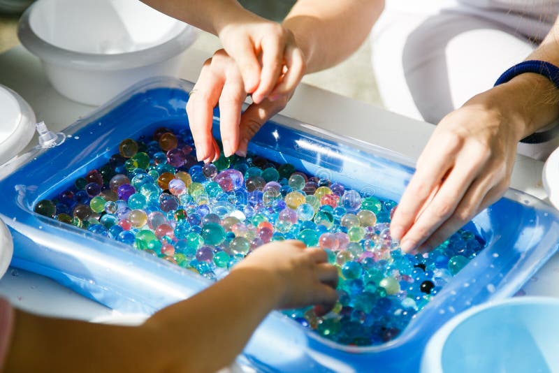 child playing with colored glass ball, playing game with colored balls