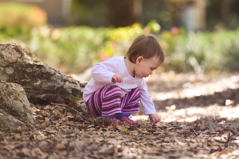 Child playing at a park picking up rocks