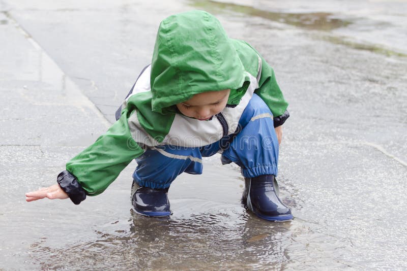 Child playing and splashing water in a puddle,. Child playing and splashing water in a puddle,