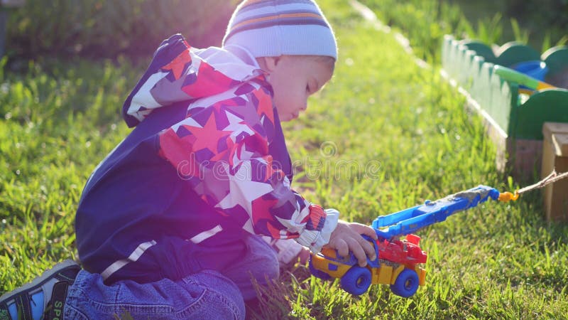A child plays with a toy car on the lawn. Fun and games outdoors royalty free stock photography A child plays with a toy car on the lawn. Fun and games outdoors royalty free stock photography