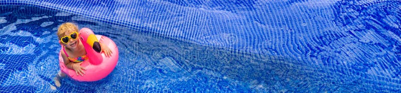 A child in a pool swims in a circle of flamingos. Selective focus. royalty free stock photography