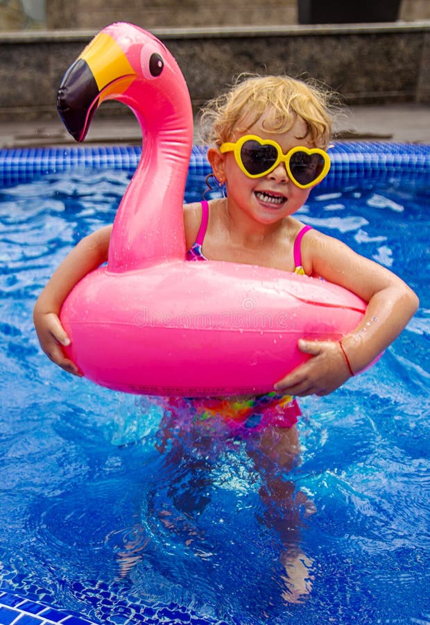 A child in a pool swims in a circle of flamingos. Selective focus. stock photo