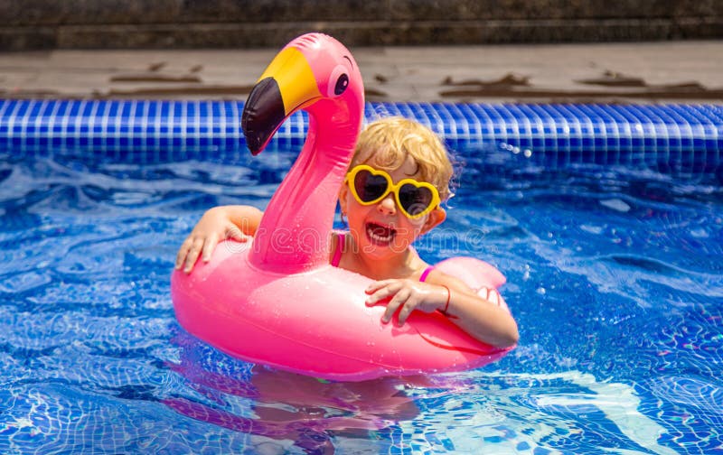 A child in a pool swims in a circle of flamingos. Selective focus. royalty free stock photos
