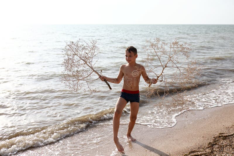 Child posing with tumbleweed plant on beach of Azov sea