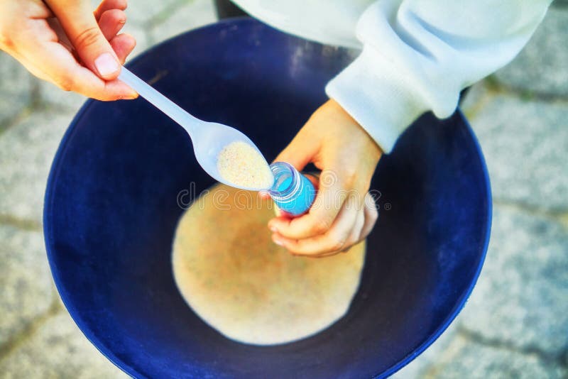 Child pour colored sand in the bottle