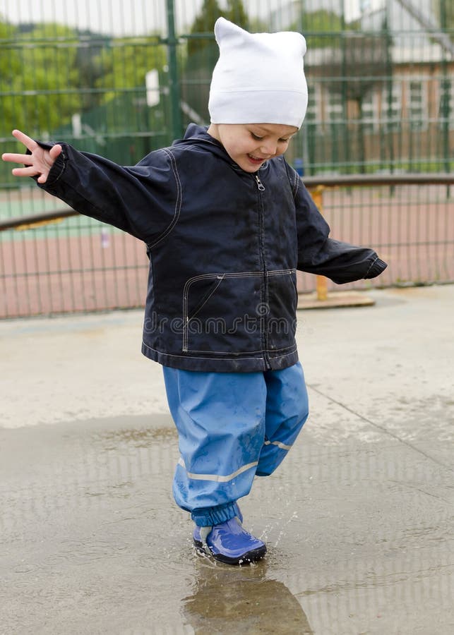 Happy child toddler playing in puddle after rain. Happy child toddler playing in puddle after rain.