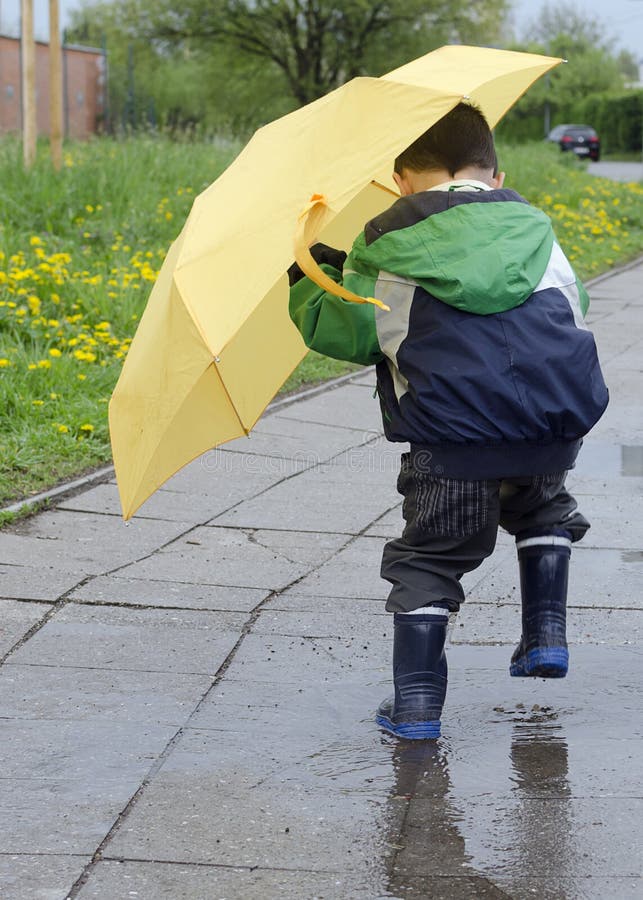 Child with a yellow umbrella jumping into a puddle after the rain. Child with a yellow umbrella jumping into a puddle after the rain.