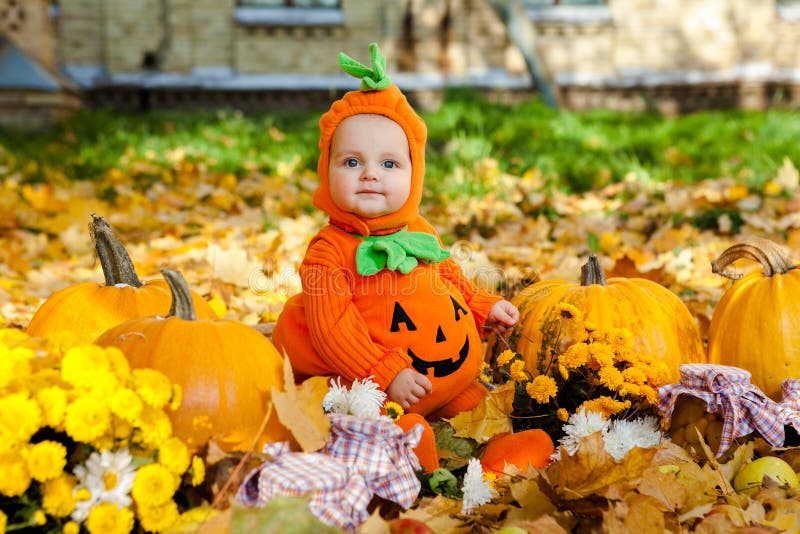 Child in pumpkin suit on background of autumn leaves