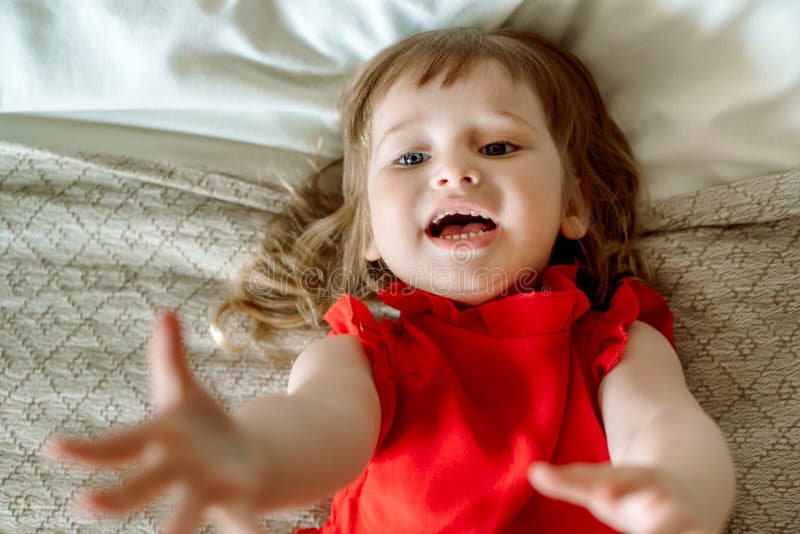 The Child Reaches Up, Cries and Calls. Emotional Cute Baby in a Bad Mood, Angry and Sad. Lying on the Bed.asks for Help, Top Stock Photo - Image of cheerful, looking: