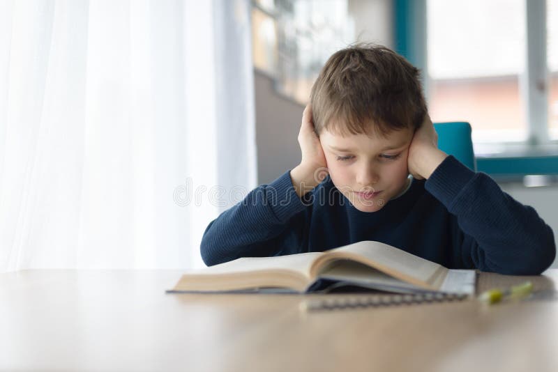Child reading a book at the desk stock image
