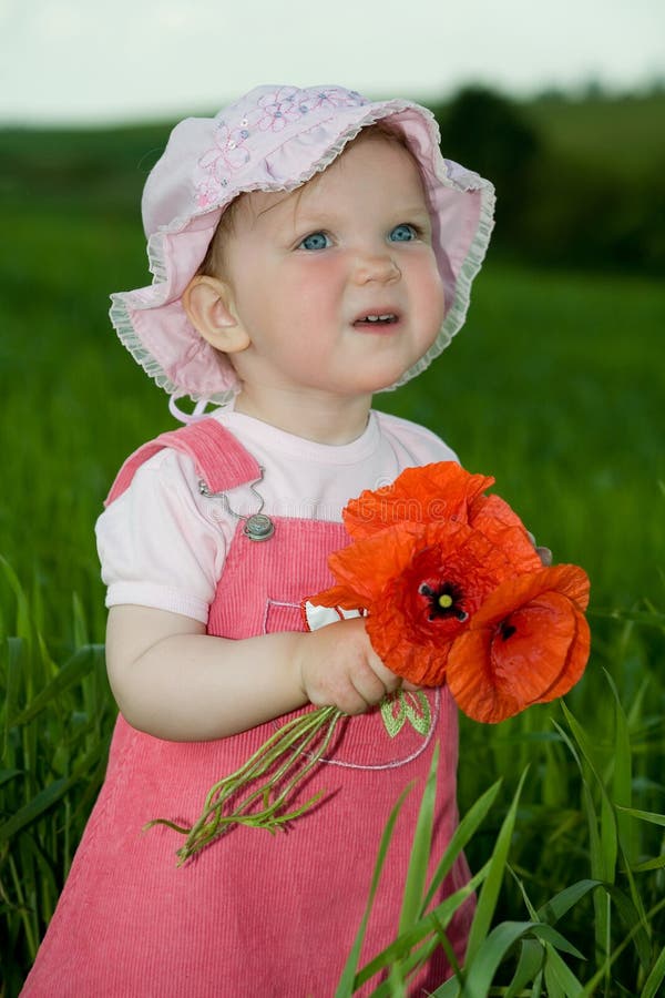 Child with red flower amongst green grass