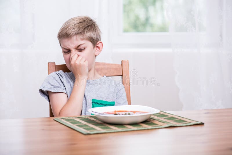 Dieťa sedí pri stole a odmietajú jesť polievku.