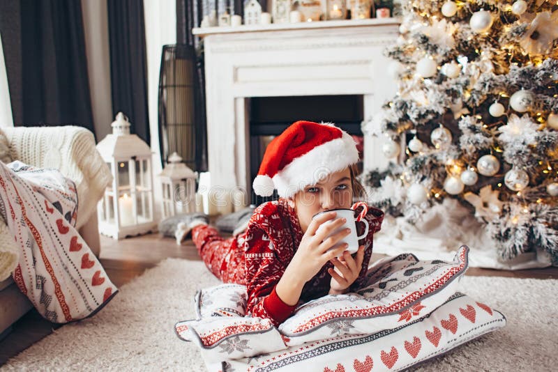 Child relaxing by Christmas tree at home