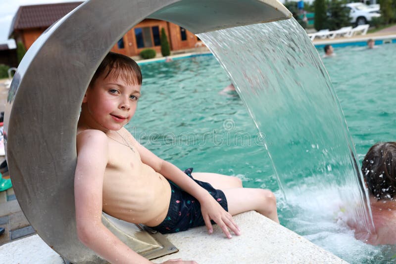 Child resting under stream of water in pool royalty free stock images