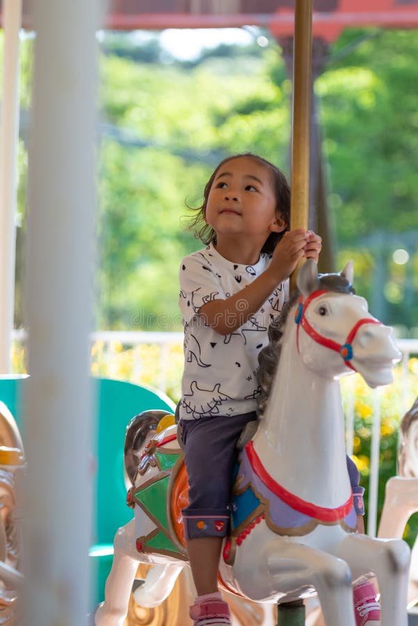 A child riding on a horse carousel merry go round. stock illustration