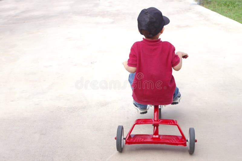 A young boy on a classic red tricycle, with copy space on left side. A young boy on a classic red tricycle, with copy space on left side