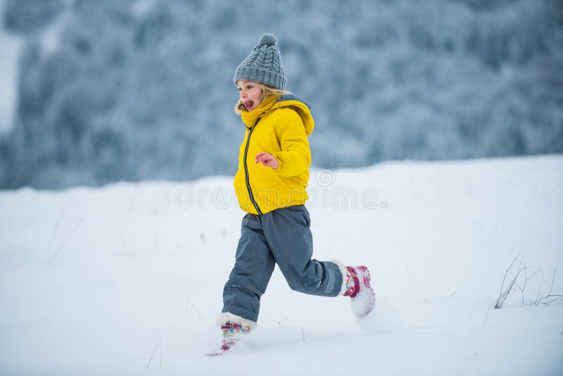 Child running on snow in winter. Kids playing and jumping in snowy forest. A kid runs through the snow. stock images