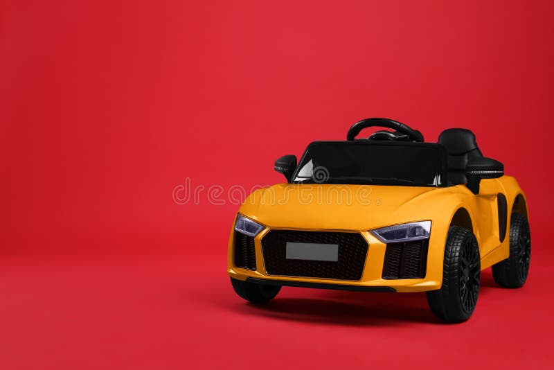 Child`s electric toy car on red background. Space for text