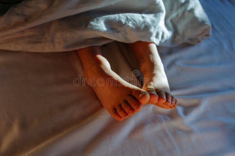 Child& X27;s Feet Under Grey Blanket in the Early Morning Light Stock