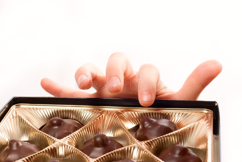 Child s hand picking chocolate candy from box isol