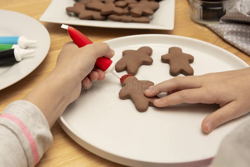 Child& x27;s hands decorating a christmas gingerbread cookies using colored glazeon, wooden table, top view. Christmas cookies royalty free stock photos Child& x27;s hands decorating a christmas gingerbread cookies using colored glazeon, wooden table, top view. Christmas cookies royalty free stock photos