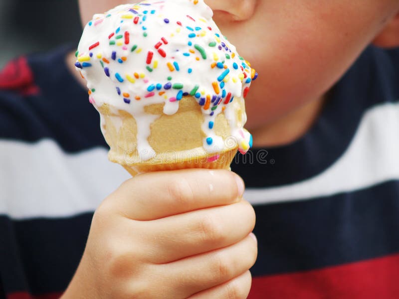 Mladý childs ruke drží odkvapkávanie zmrzlinu kužeľ s farebnými postrekovačov.