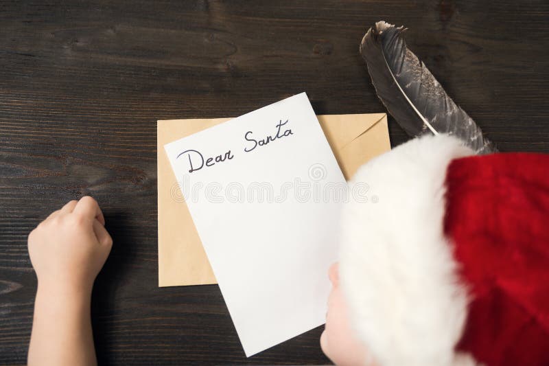 Child in Santa hat is sleeping at the table. Letter for Santa. Wooden background stock photos Child in Santa hat is sleeping at the table. Letter for Santa. Wooden background stock photos