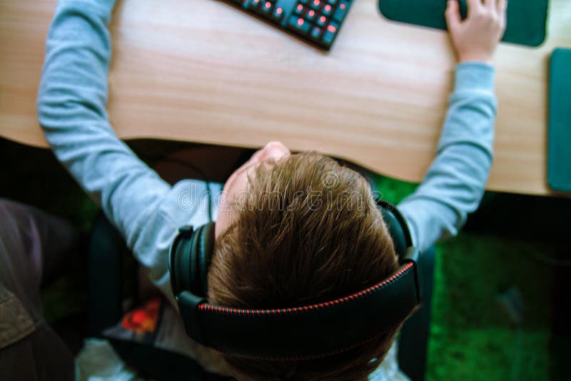 The child sits at the computer and plays computer games in the headphones. Top view of the hand holding the mouse and keyboard. stock image The child sits at the computer and plays computer games in the headphones. Top view of the hand holding the mouse and keyboard. stock image