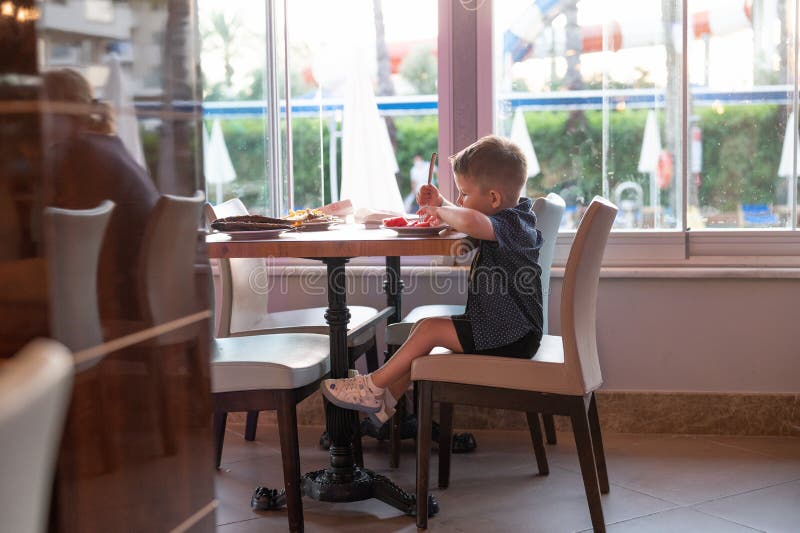 The Child is Sitting Alone in a Restaurant Stock Photo Image of