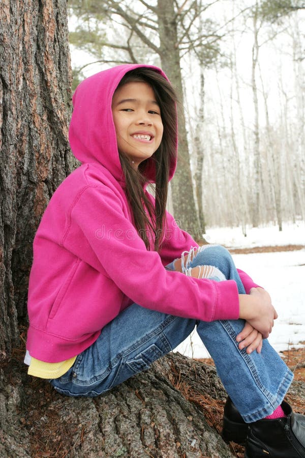 Child sitting under tree in winter