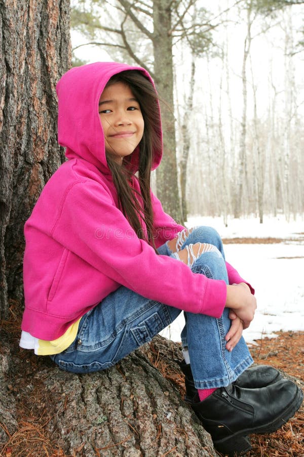 Child sitting under tree in winter