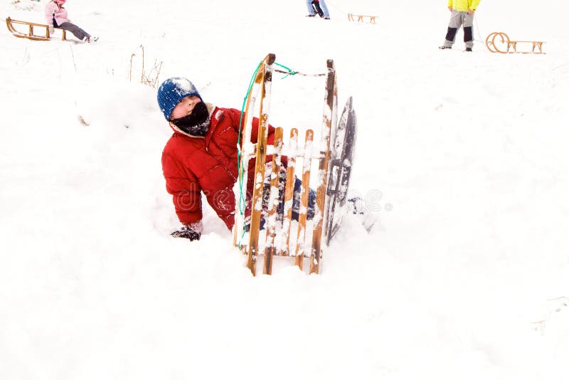 Child sledding down the hill in snow, white winter