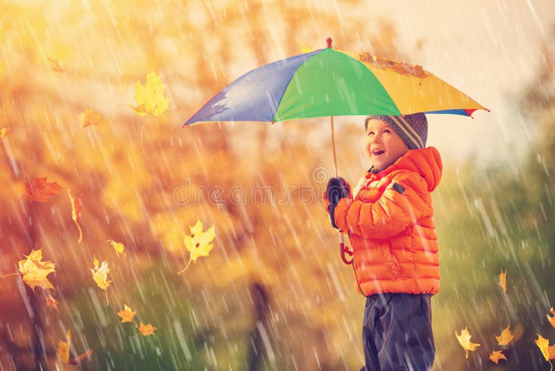 Child standing with umbrella in beautiful autumnal day