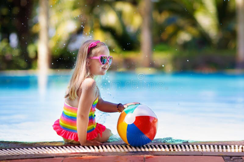 Child in swimming pool with ball. Kids swim