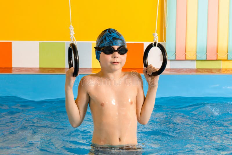 Child in swimming pool excersizing with sport rings