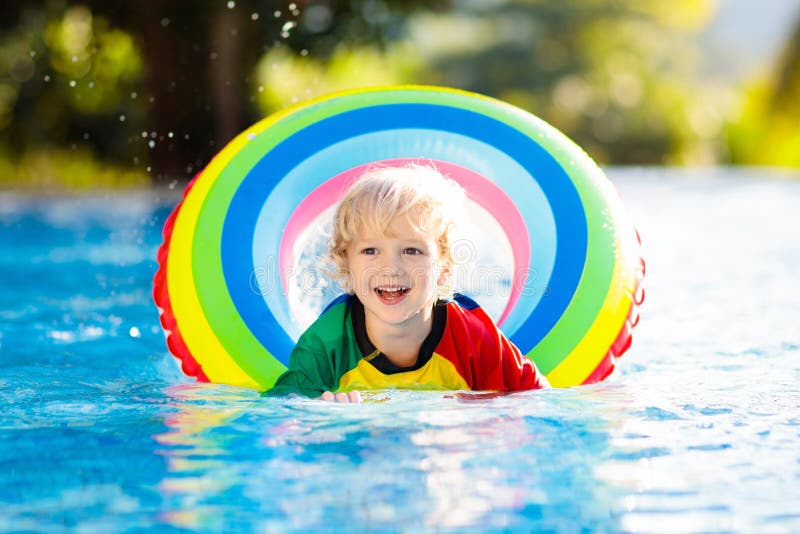 Child in swimming pool on toy ring. Kids swim