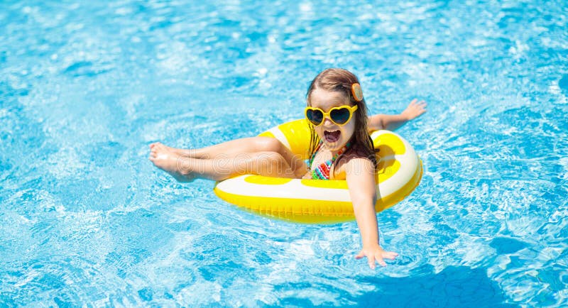 Child in swimming pool on ring toy. Kids swim