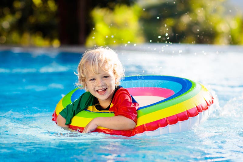 Child in swimming pool on toy ring. Kids swim