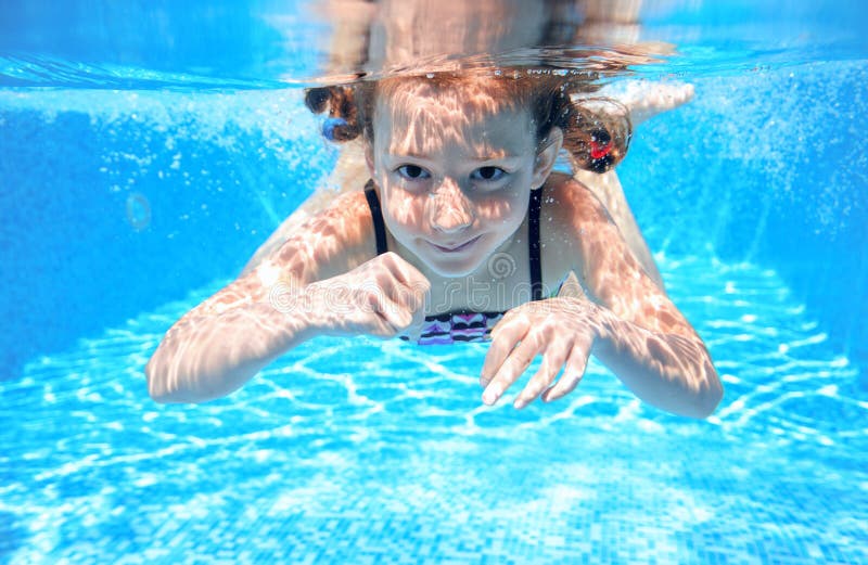 Child swims in pool underwater, happy active girl has fun